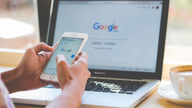 Seseorang membuka laman Google di smartphone dan laptop